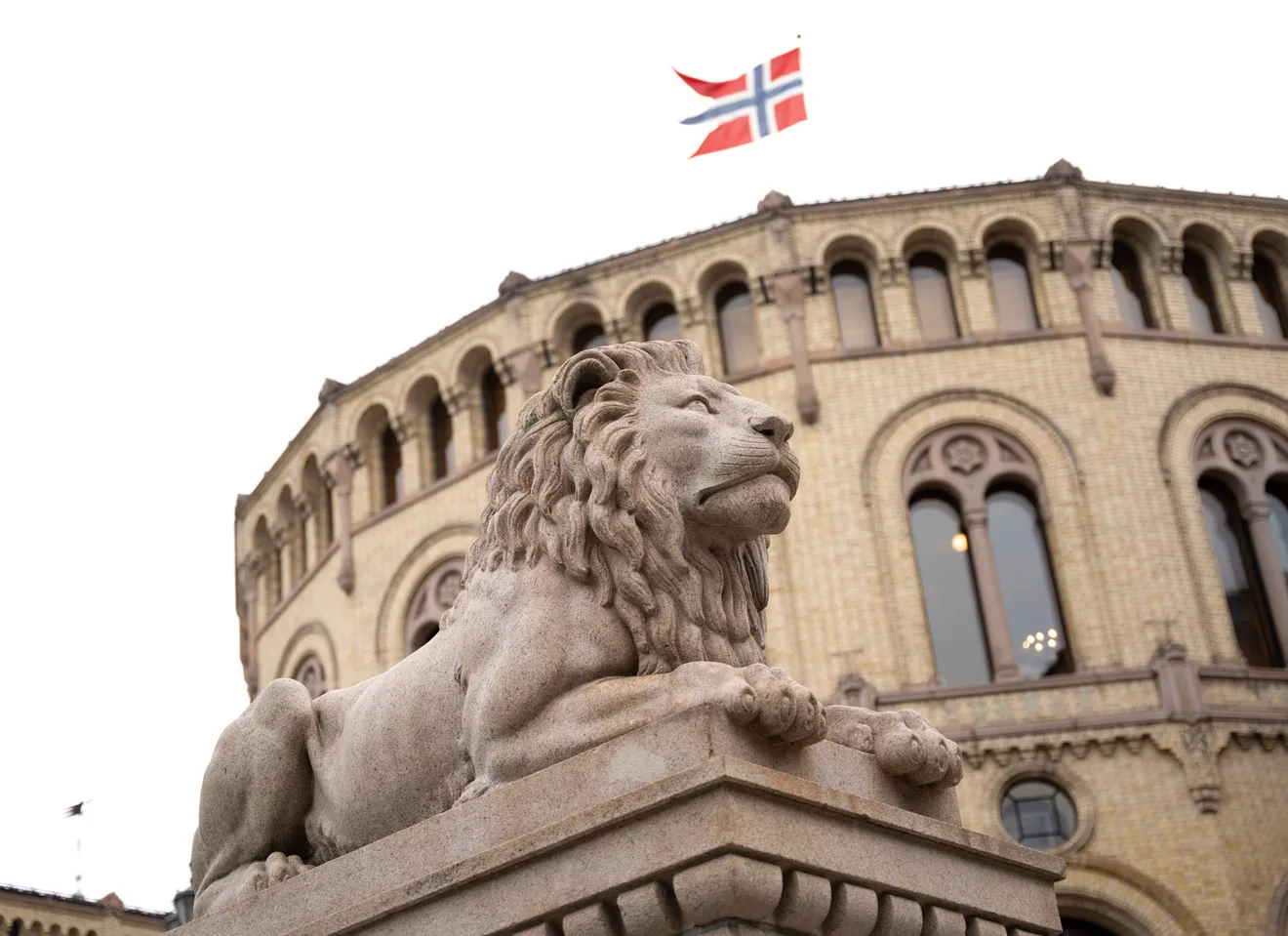 Løven foran Stortinget og flagg som vaier på toppen av bygget
