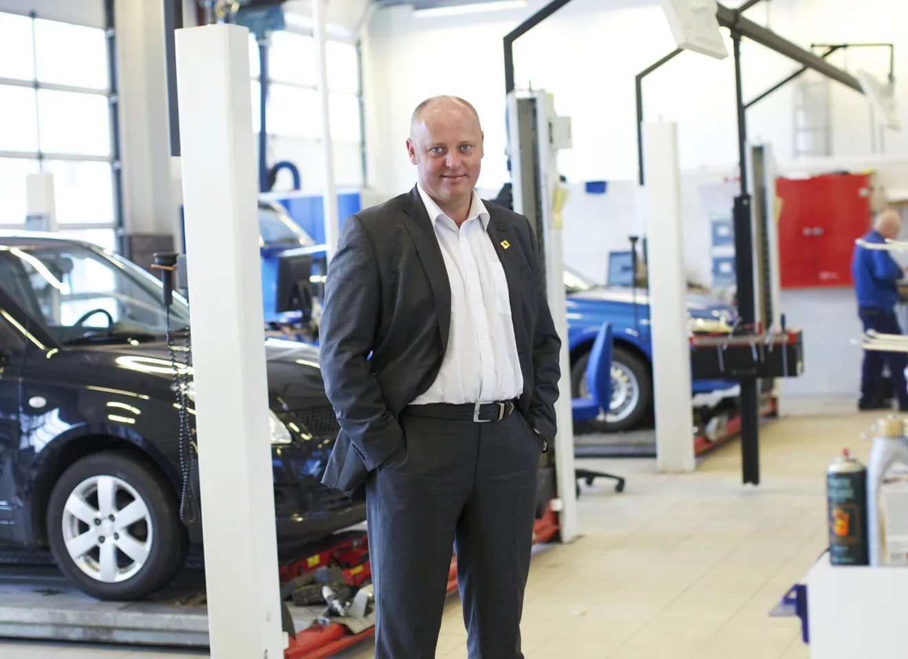 Stig Skjøstad står foran flere biler i et bilverksted
