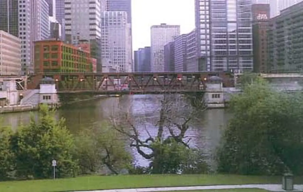 Brun bru over en elv med skyskrapere i bakgrunn