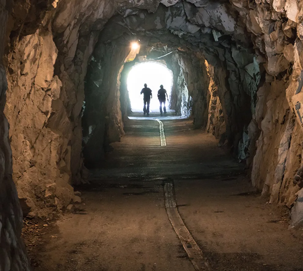 To arbeidere på vei ut av en tunnel i  fjellet