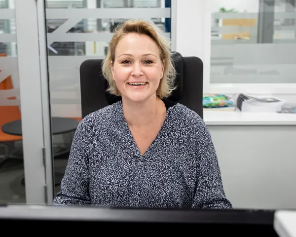 Katrine Olsson sitter på kontoret og smiler til kamera