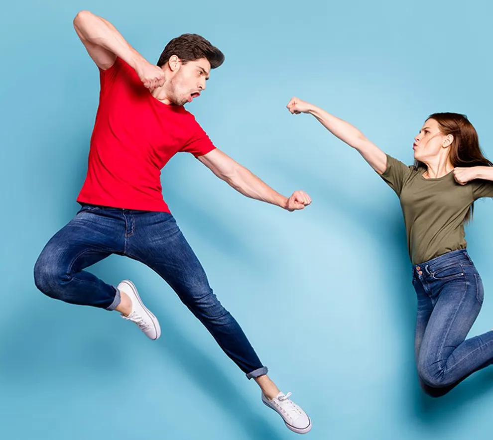 En mann og en kvinne som hopper og viser knyttnever mot hverandre