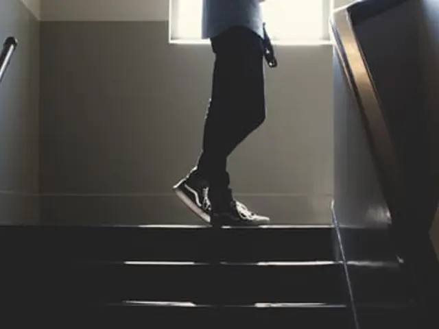 Beina til en person som går opp en mørk trapp