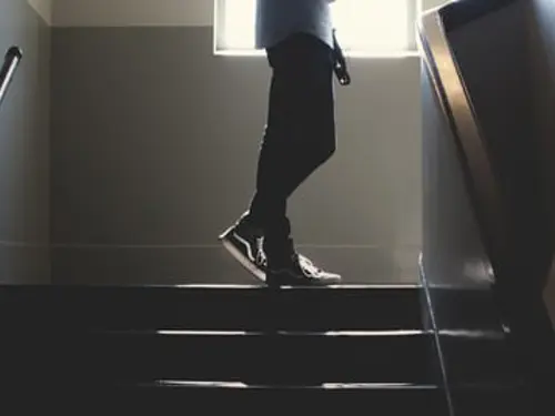 Beina til en person som går opp en mørk trapp
