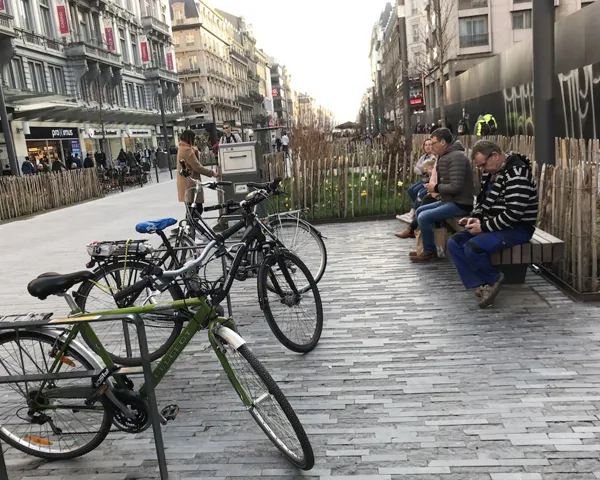 En gågate i Brussel med planter, sitteplasser, mennesker og sykkler