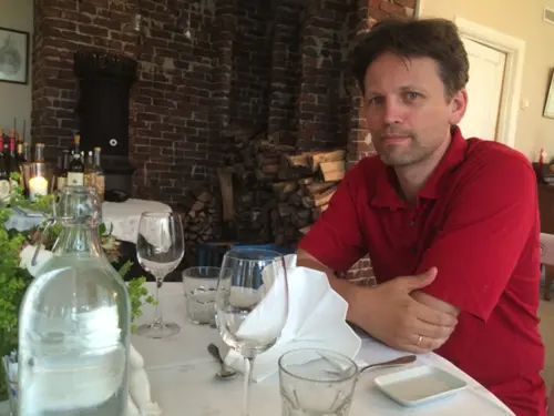 Øystein Vandvik sitter ved middagsbordet i et restaurant og smiler til kamera