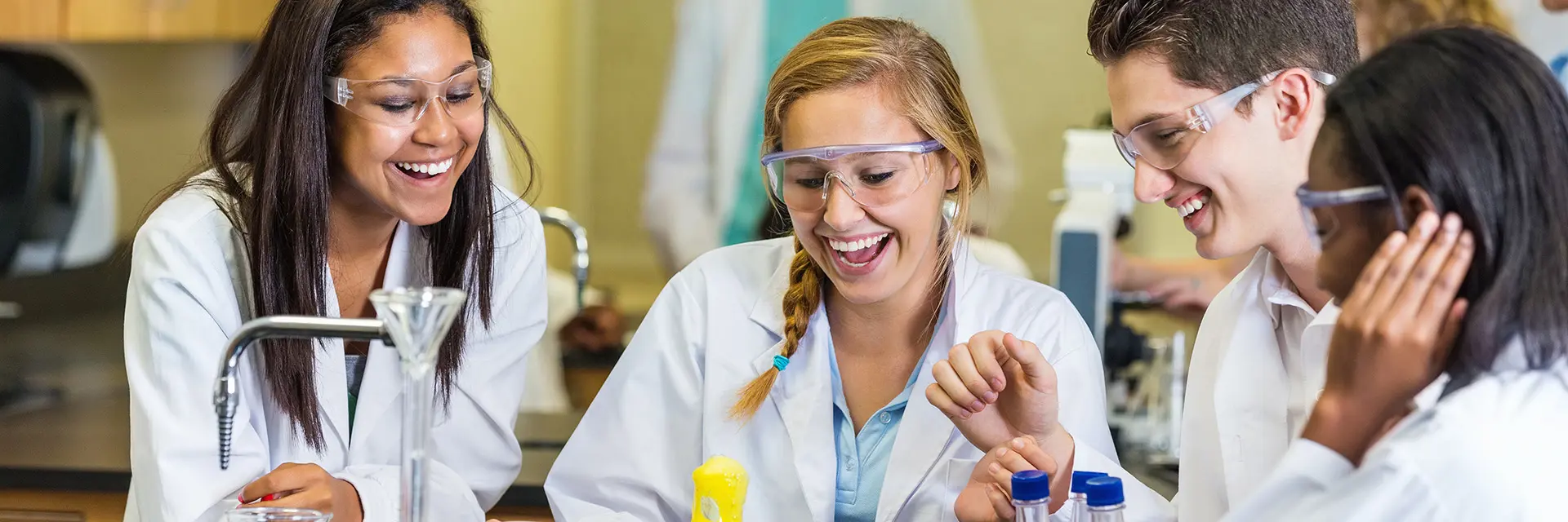 Illustrasjonsbilde av studenter i laborutstyr som smiler