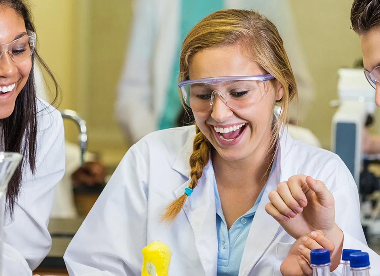 Illustrasjonsbilde av studenter i laborutstyr som smiler