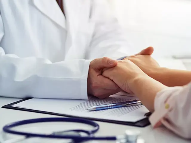 lege holder hender til pasient