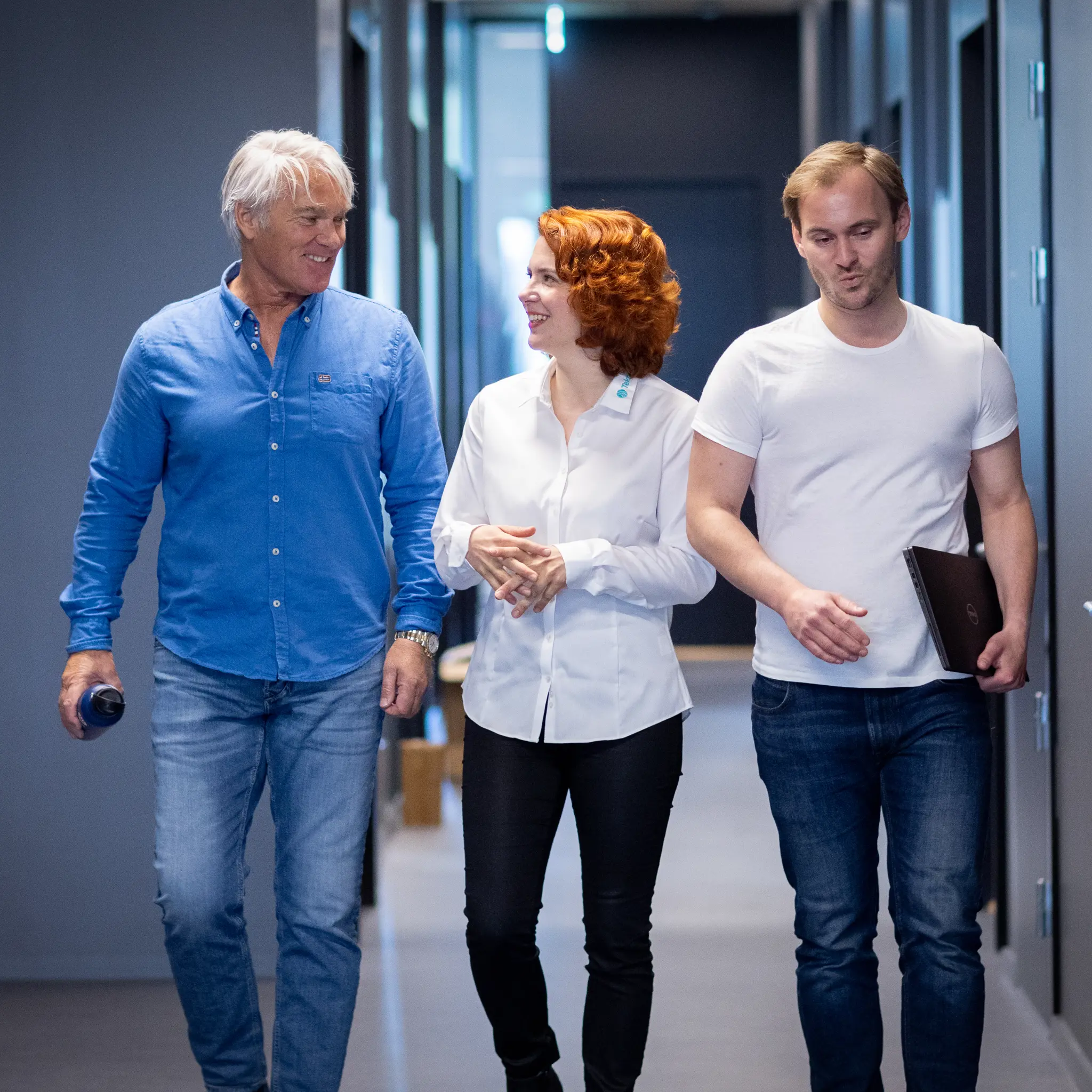 Tre personer som går i en gang