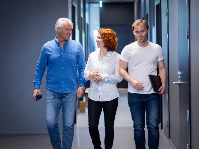 Tre personer som går i en gang