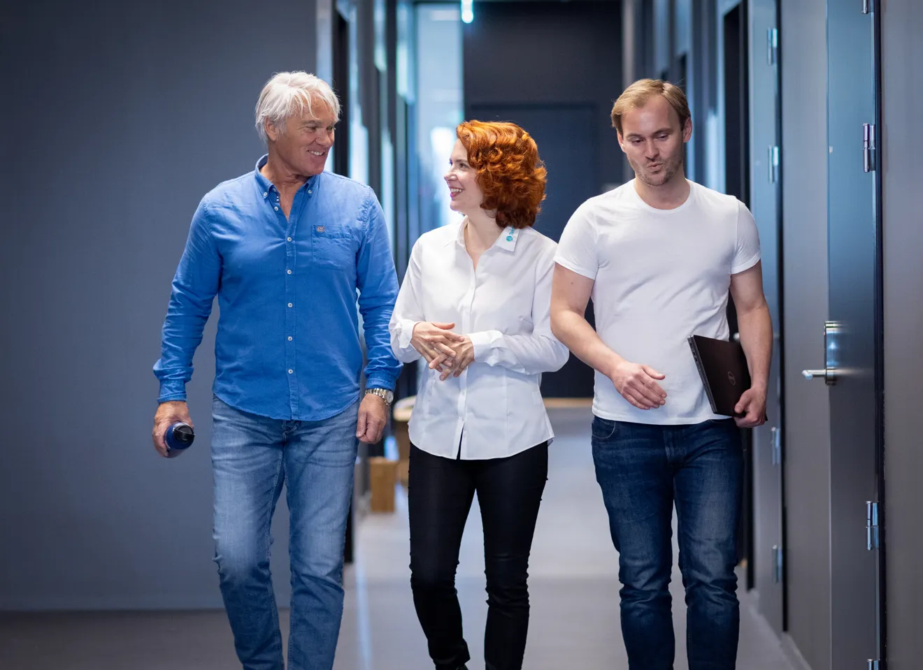 Tre personer som går i en gang