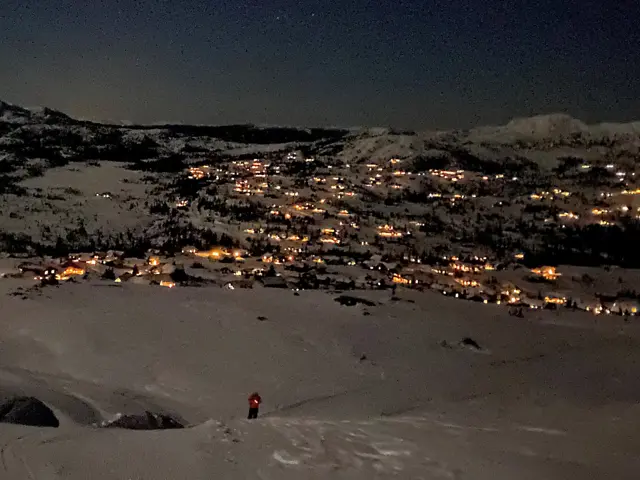 Snødekket fjell med lys fra hytter om natten