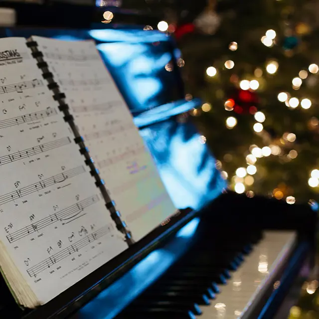 Piano med noteark, juletre i bakgrunnen