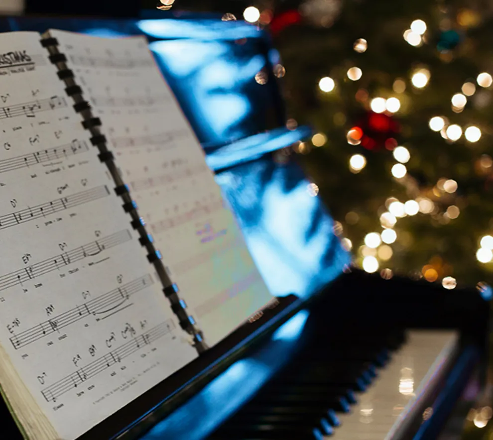 Piano med noteark, juletre i bakgrunnen