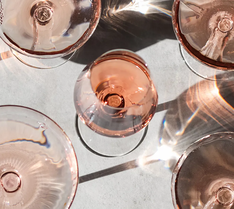 Glass med rosé og bobler på et bord, sammen med jordbær, rips og bringebær sett ovenfra