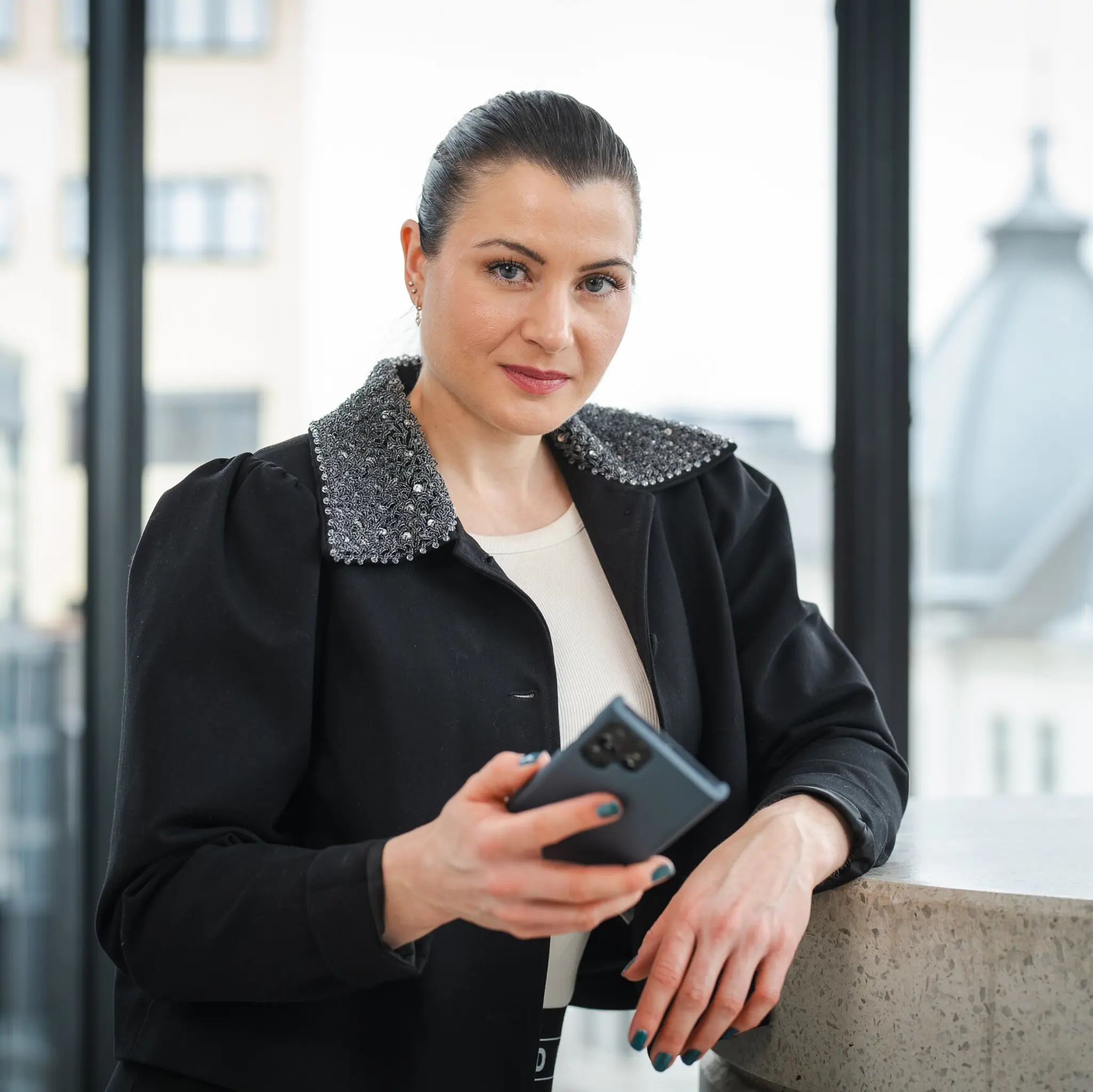 President Elisabet Haugsbø inne i kontorlandskap, med mobil i hånda, svarte klær, alvorlig ansiktsuttrykk