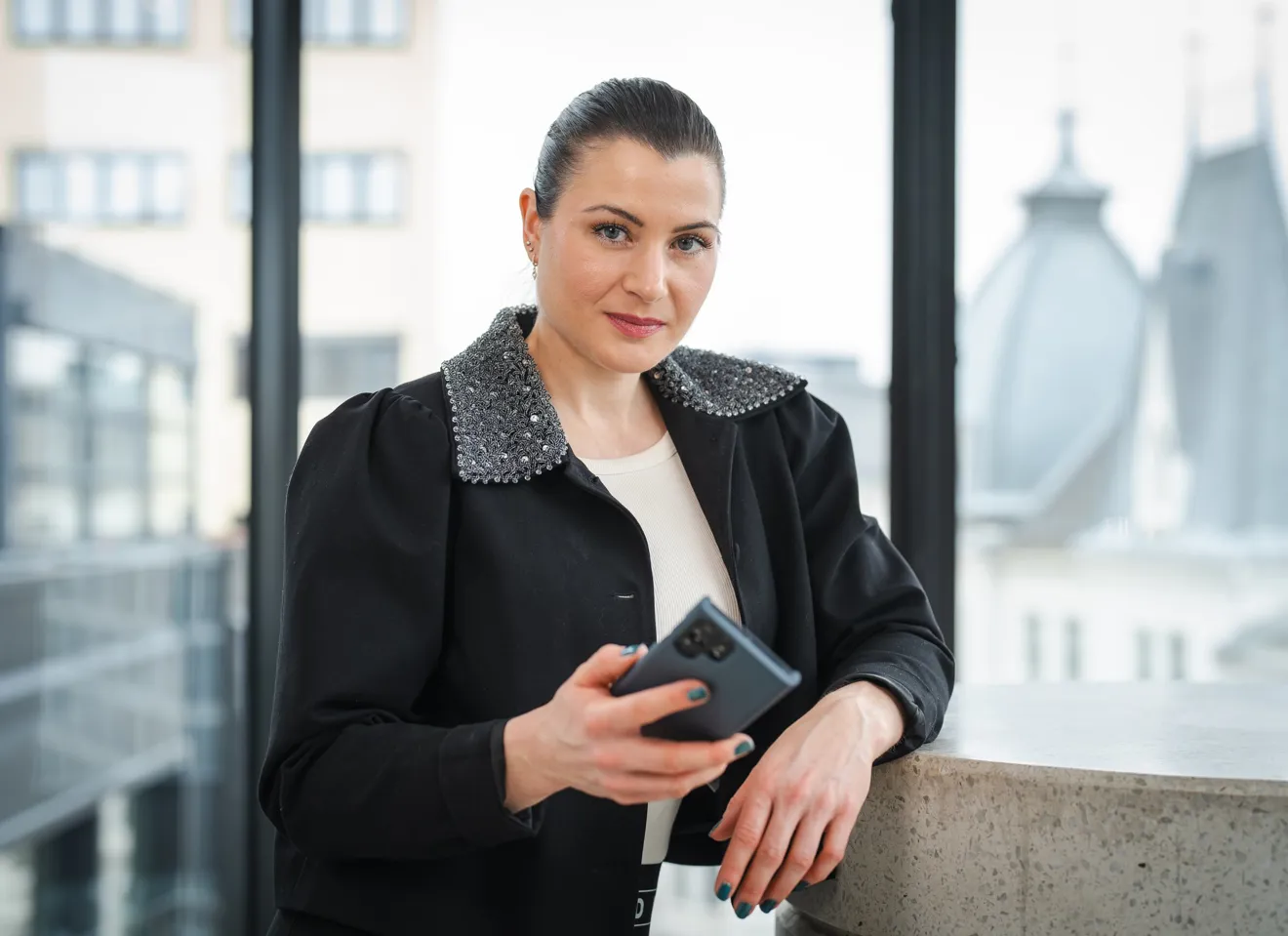 President Elisabet Haugsbø inne i kontorlandskap, med mobil i hånda, svarte klær, alvorlig ansiktsuttrykk
