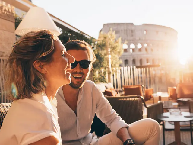 Mann og kvinne på fortauskafé i solnedgang med Colosseum og Roma i bakgrunnen. 