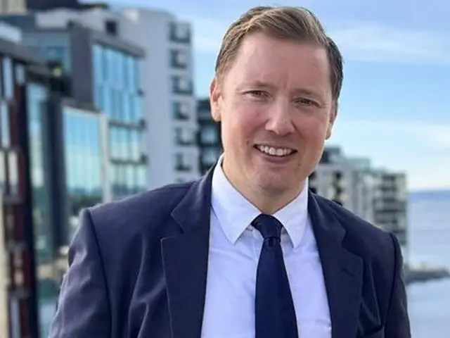 Mann med dress ser inn i kamera