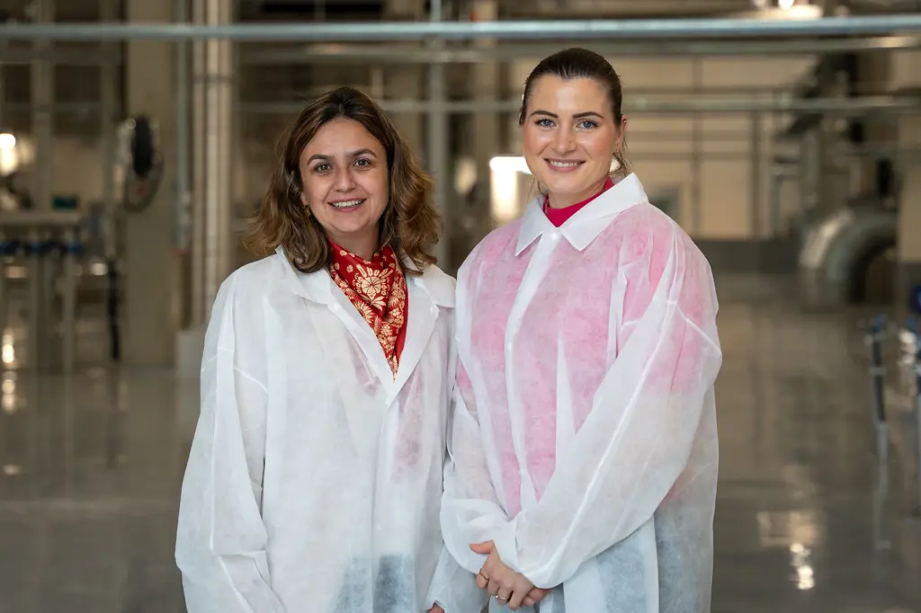 Asude Sørensen og Elisabet Haugsbø, smiler, i hvite beskyttelsesfrakker