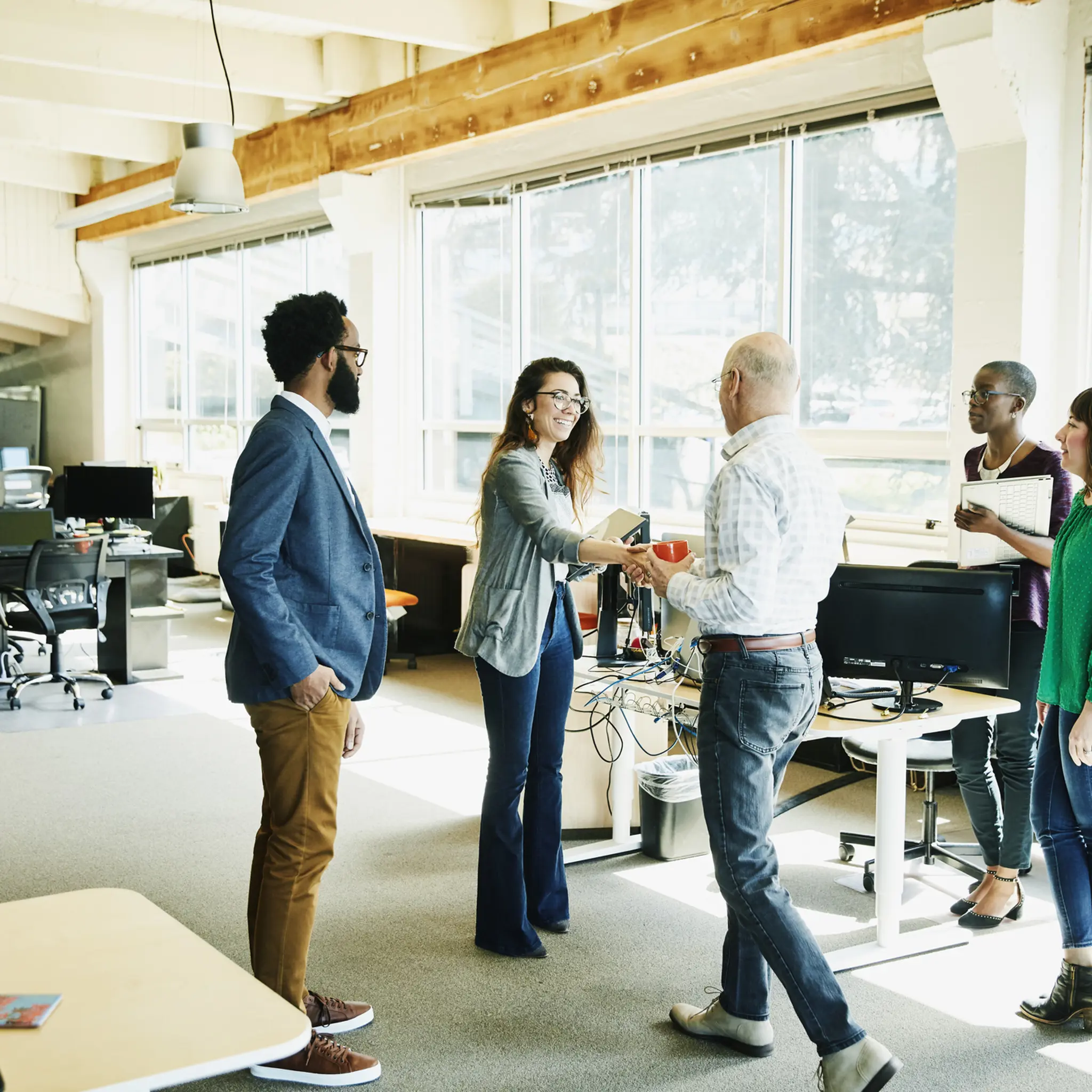 Illustrasjonsbilde av flere ansatte i et kontorlandskap hilser på hverandre