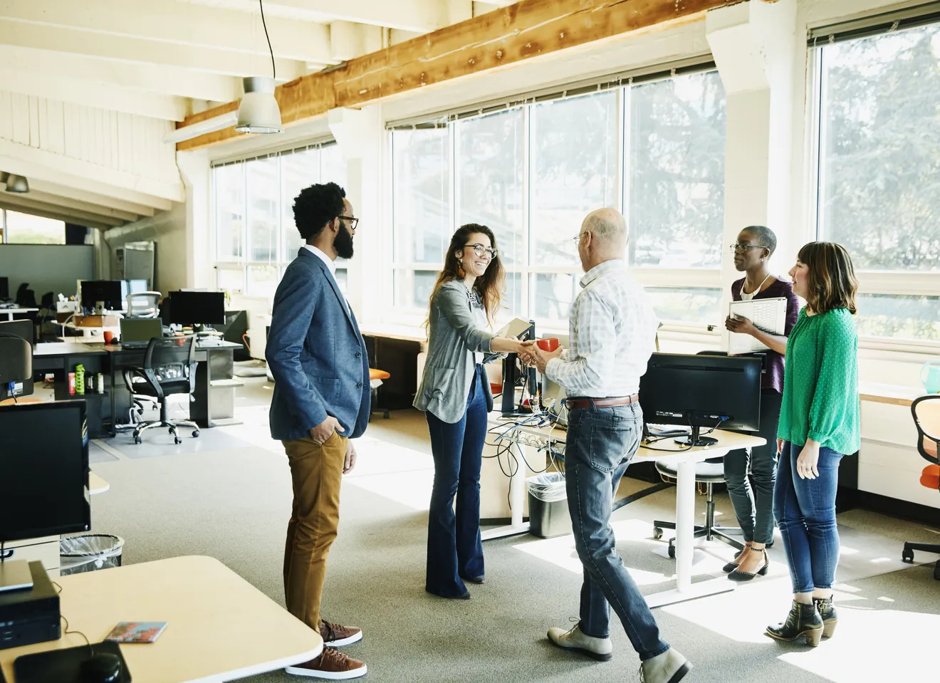 Illustrasjonsbilde av flere ansatte i et kontorlandskap hilser på hverandre