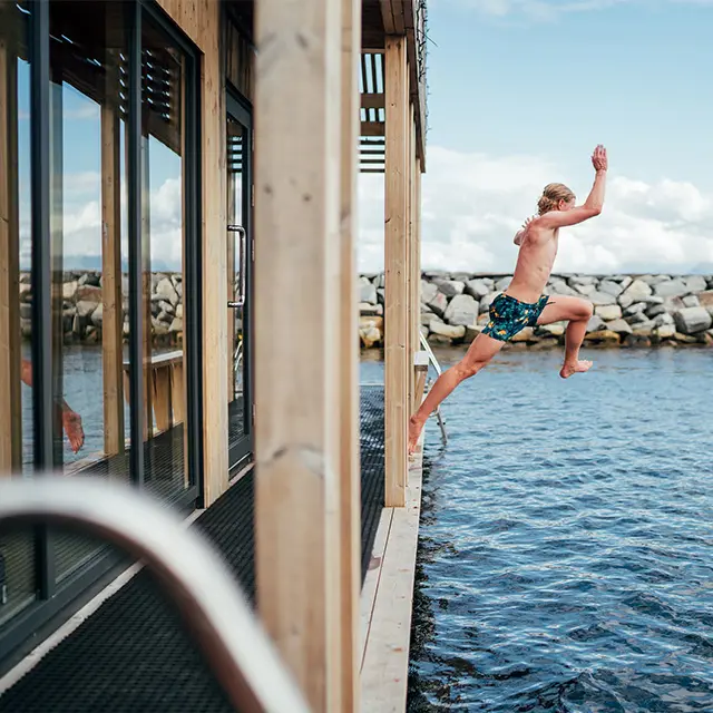 Mann som hopper i vannet ut fra badstue