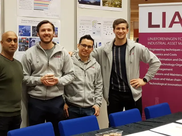 Jayantha P. Liyanage, Johannes Johannesen, Jesus Gonzalez Fernandez og Petter Senum står vedsiden av hverande foran en rollup med logo av Linjeforening Industrial Asset Management