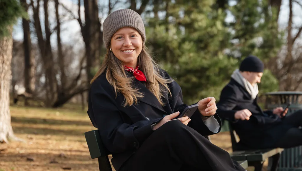 Kvinne på benk utendørs smiler