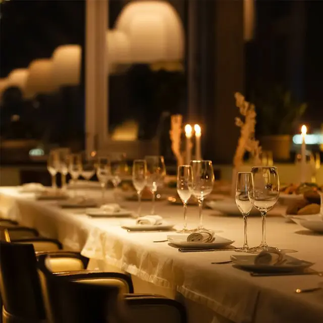 Pent dekket bord med hvite duker og stearinlys i kveldslys