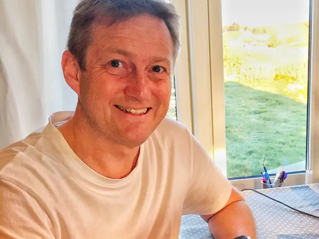 Inge Høivik ved kjøkkenbordet med en kopp kaffee