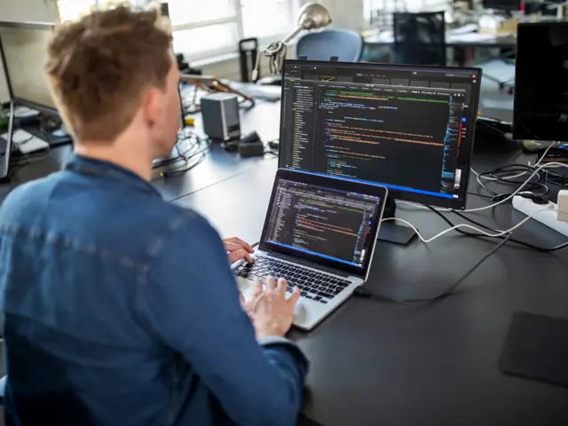 Illustrasjonsbilde av en utvikler som jobber med kildekodeutvikling på en laptop med ekstern skjerm