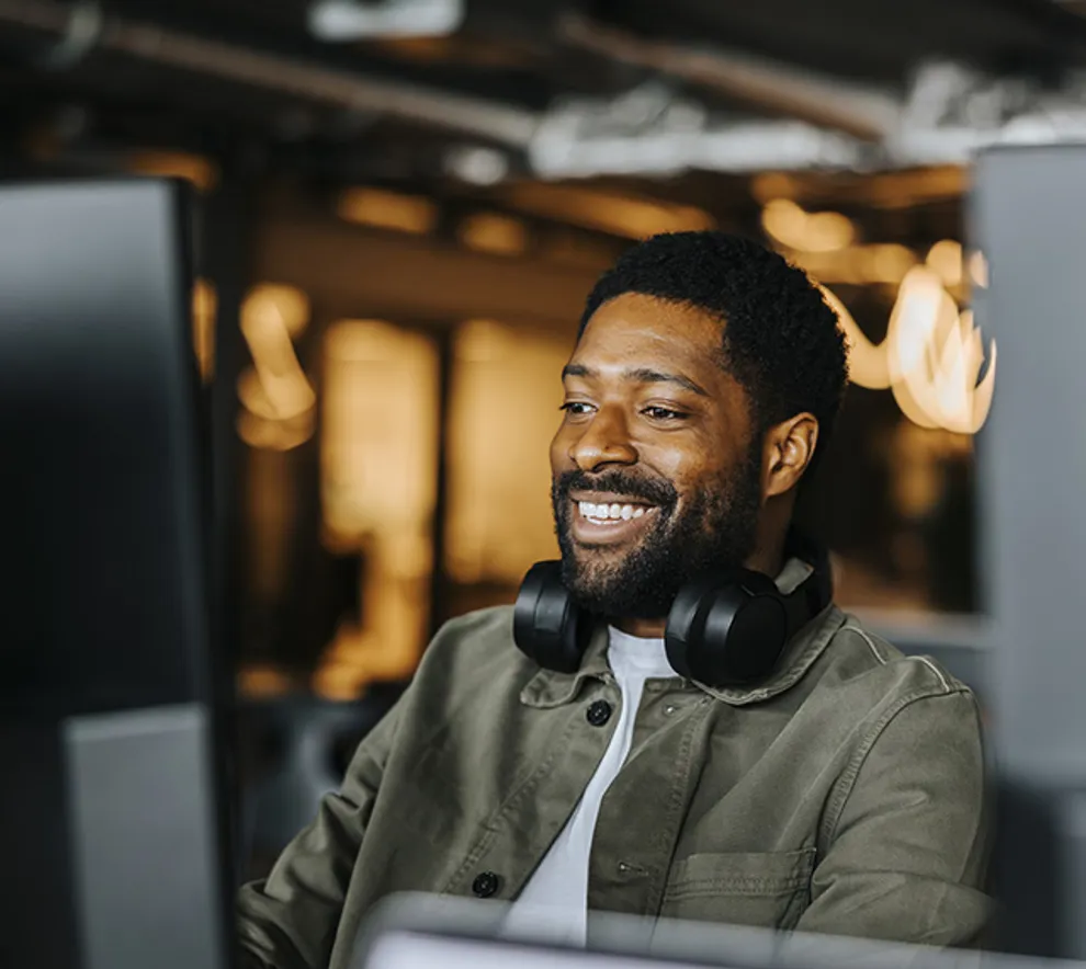 En smilende mann foran PC-en