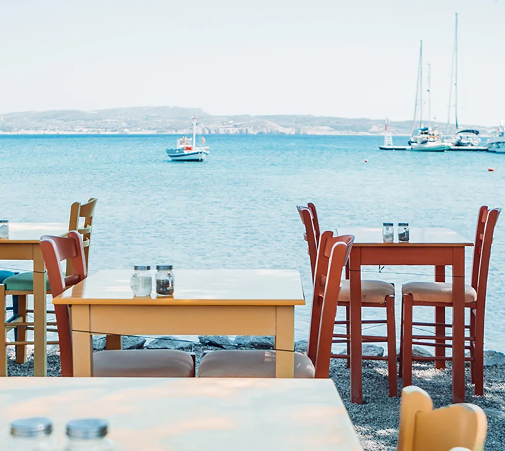 Gresk taverna med plaststoler med utsikt over havet.