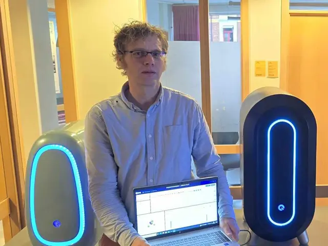 Mann står mellom to kvantedatamaskiner