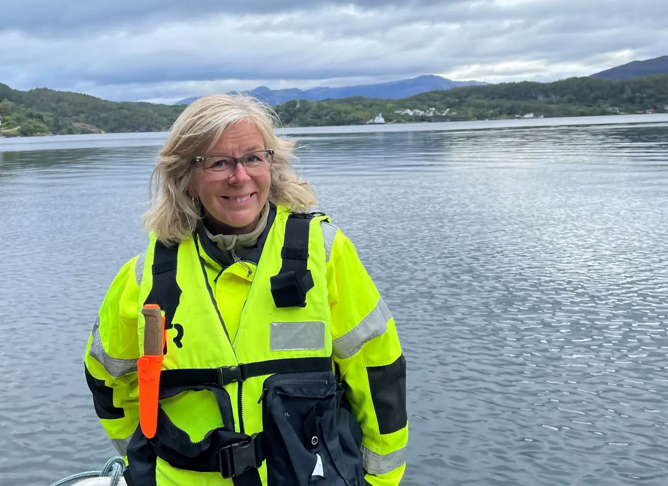 Kvinne gul jakke ved fjord