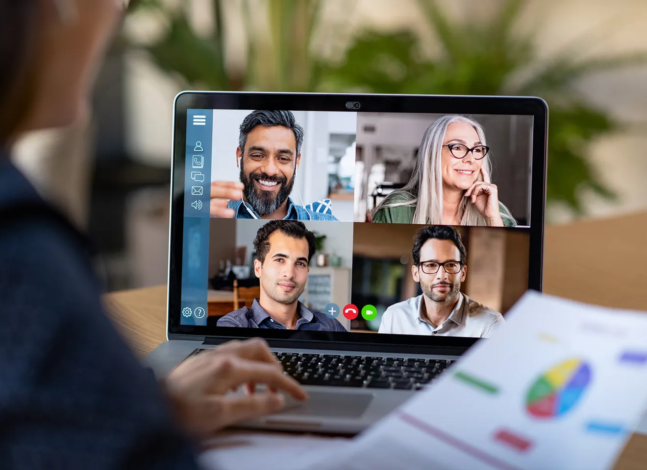 En kvinne foran en laptop som viser fire personer i et videomøte