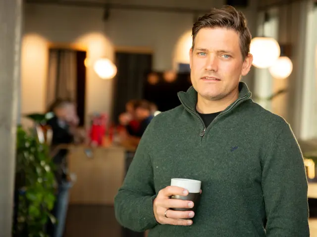 Mann står inne med kaffekopp