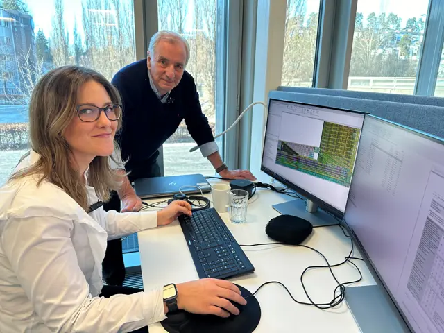 Ung kvinne og eldre mann ser på pc