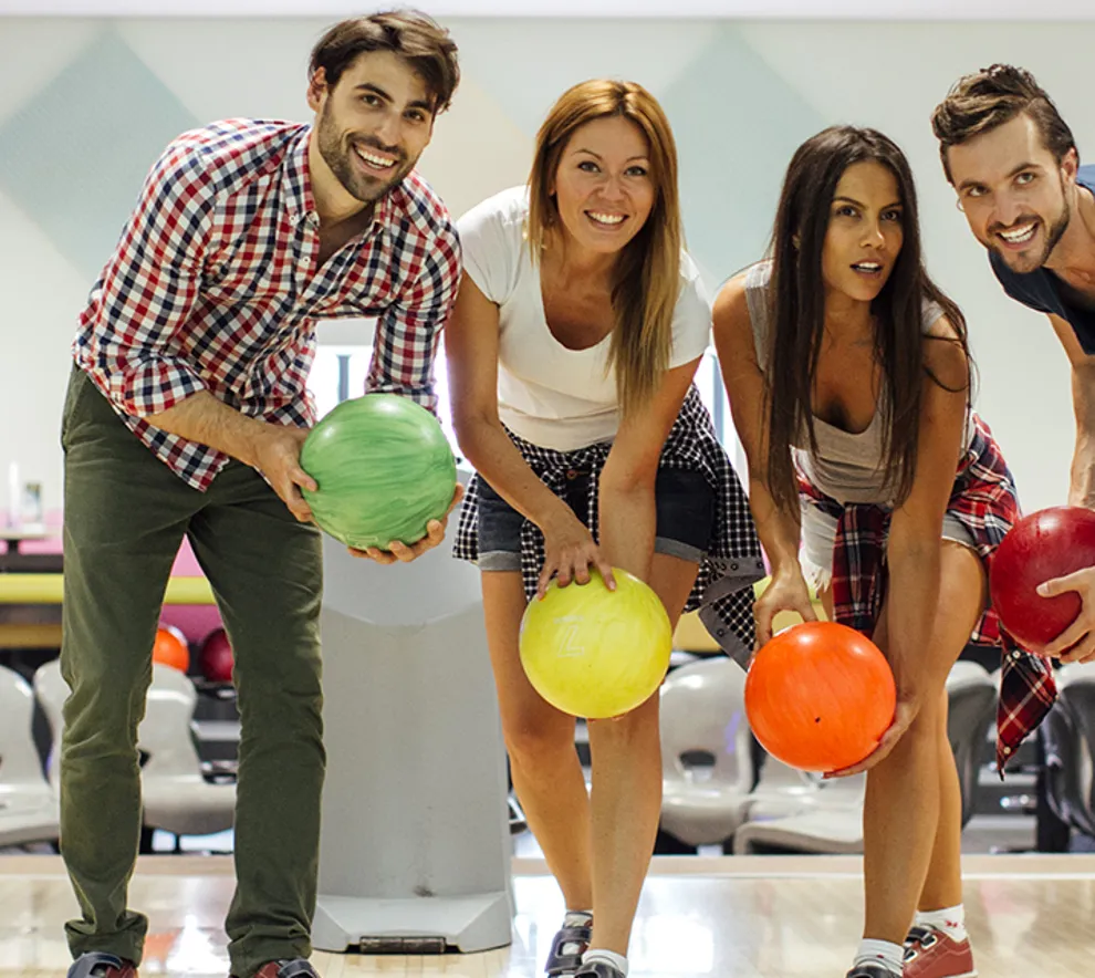 Fire venner som spiller bowling