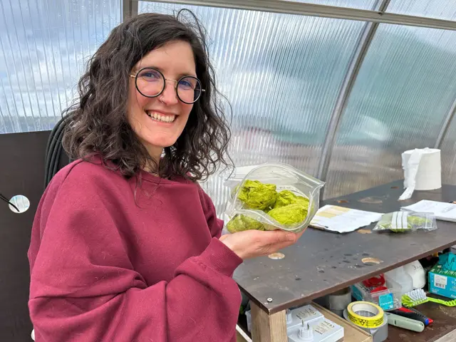 Kvinne holder grønn biomasseklump