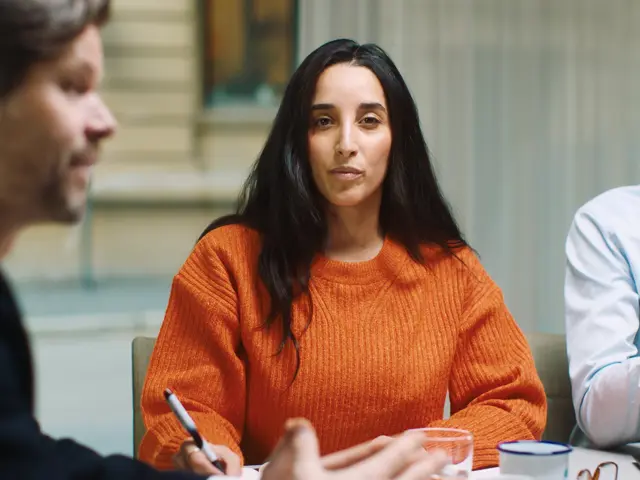 Kvinne rundt et bord ser rett inn i kameraet