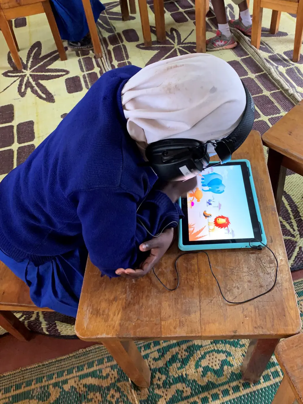 Afrikansk jente bøyd over tablet