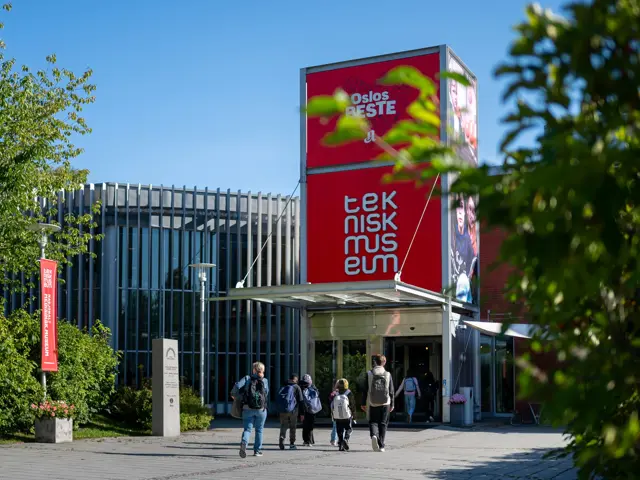 Inngangen på Teknisk museum i Oslo, blå himmel, barn som går med ryggen til mot inngangen 