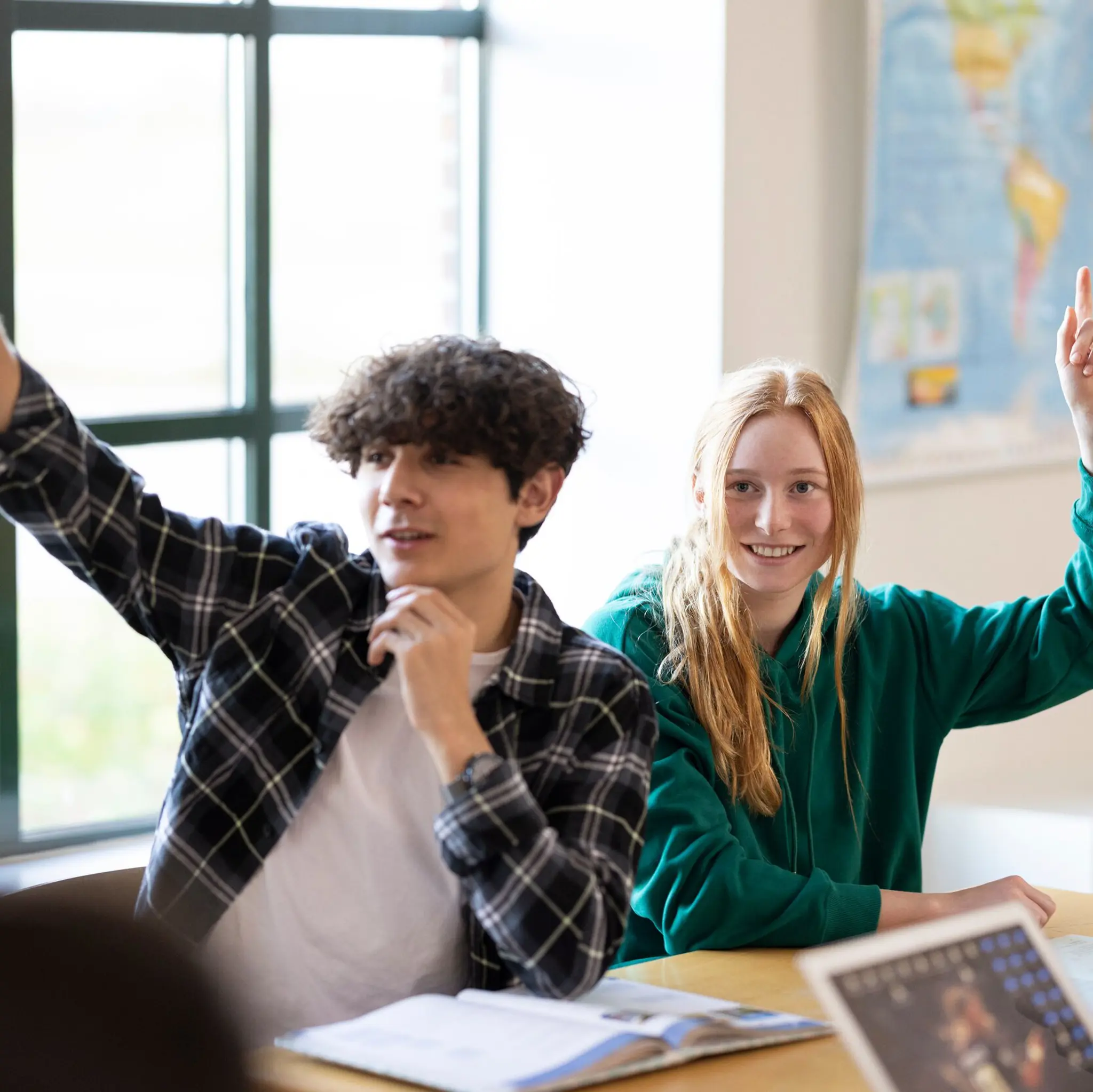 elever i klasserom rekker opp hånden