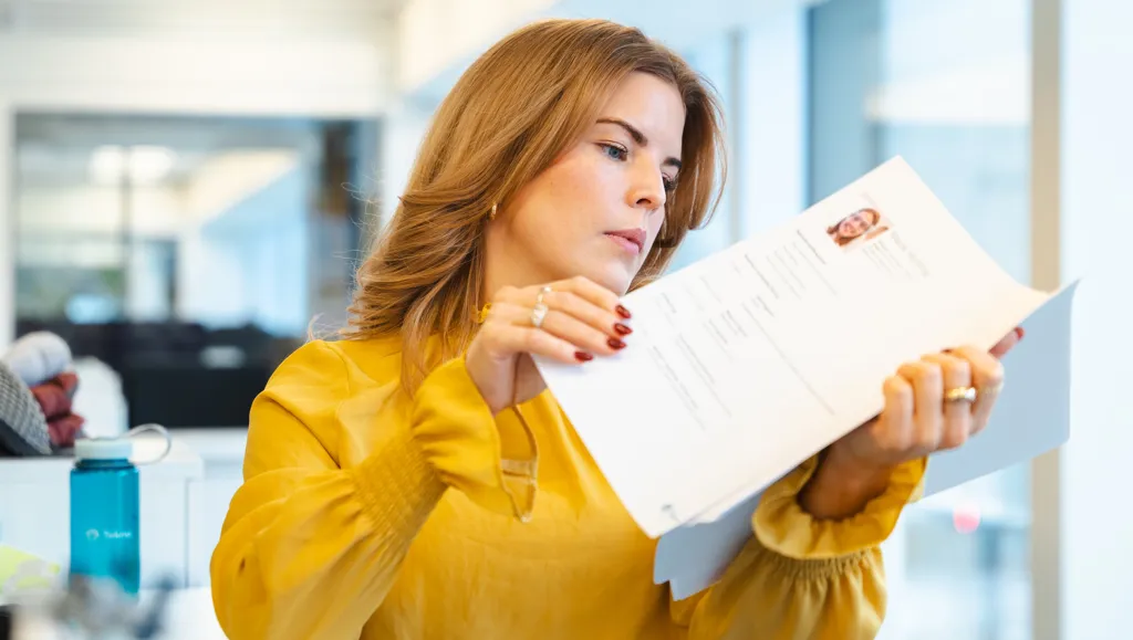 Ung kvinne ser på CV i kontorlandskap