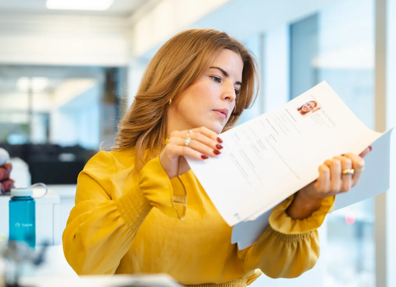 Ung kvinne ser på CV i kontorlandskap