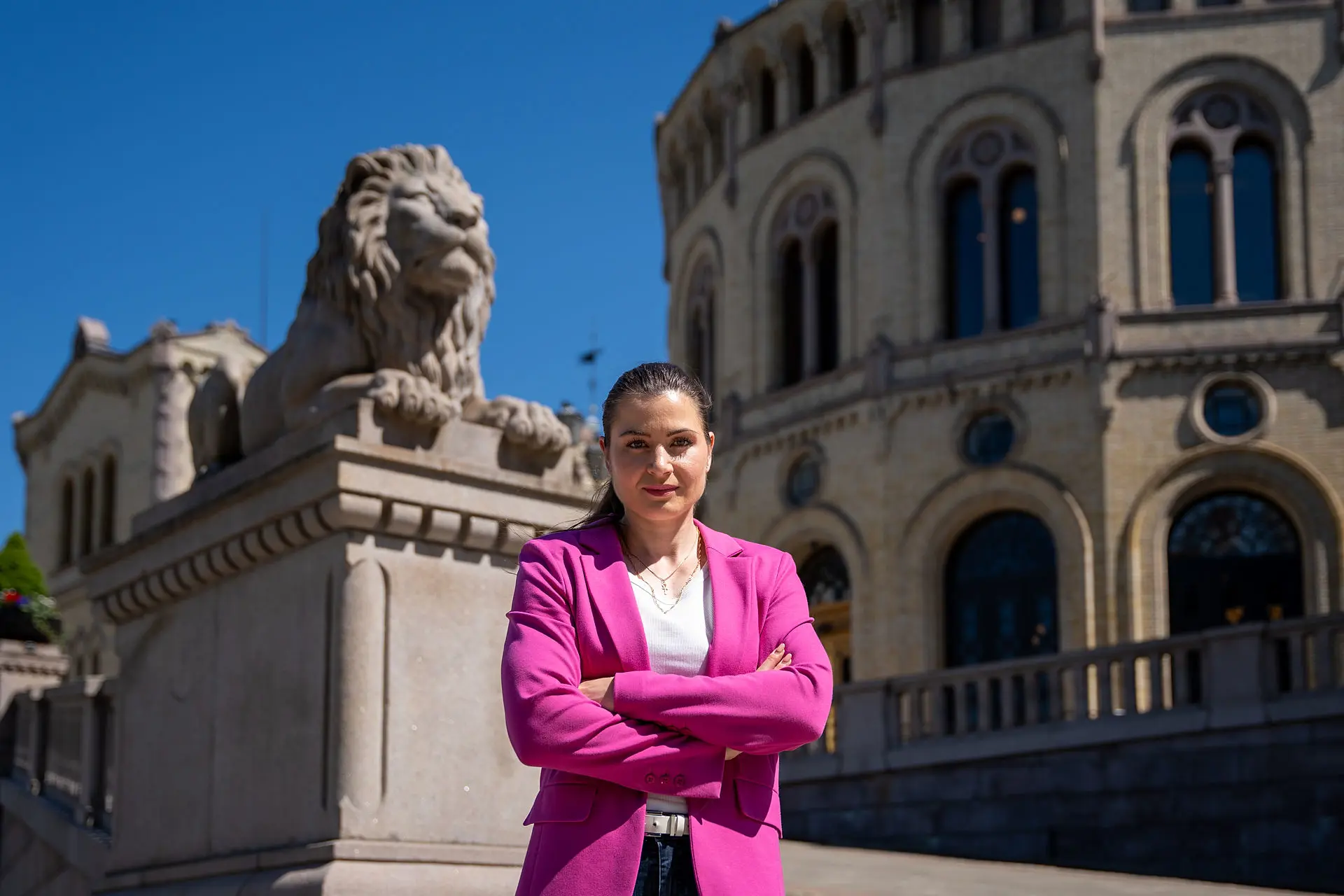 President Elisabet Haugsbø, alvorlig ansiktsuttrykk, rosa dressjakke, blå himmel, foran stortinget 