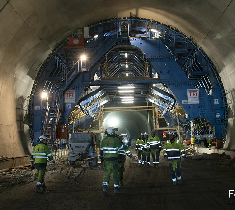 Tunnelboremaksin i fjellet mellom Nykirke og Barkåker, operatører med kjeledress og gul hjelm følger med.
